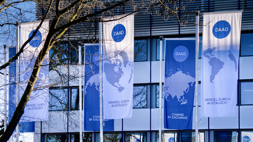 Flags with DAAD logo in front of the outer facade of the headquarters in Bonn.